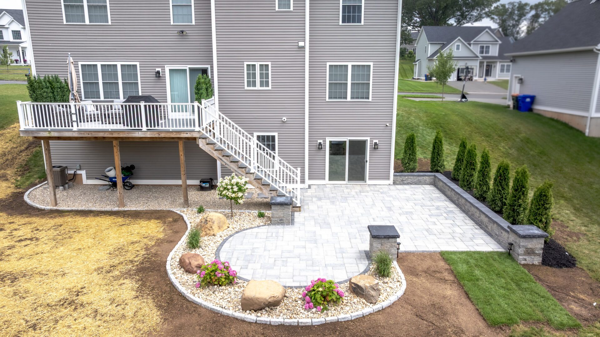Aerial view of new backyard patio installation in Connecticut with stone walls, pavers, plantings, and finished landscaping by HQ Landscaping